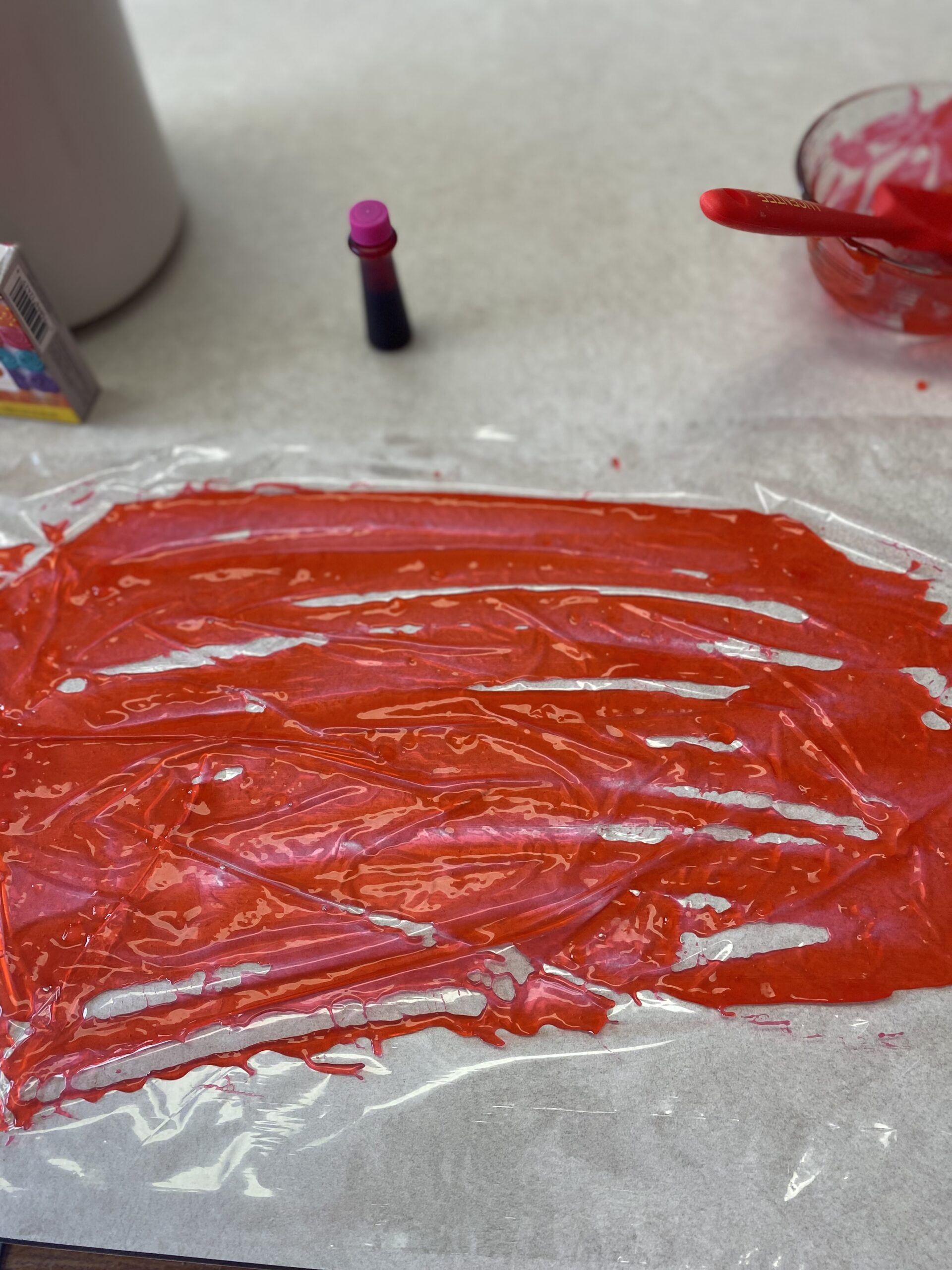 spread colored cornstarch mixture in a thin layer on a large piece of plastic wrap