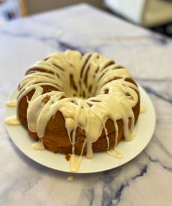 drizzle cream cheese on top of easy pumpkin spice cake with cream cheese filling