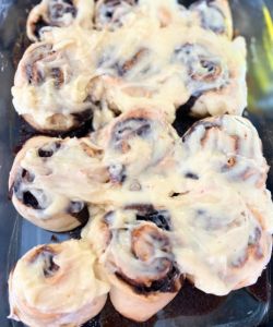 spread cream cheese frosting on easy blueberry cinnamon rolls