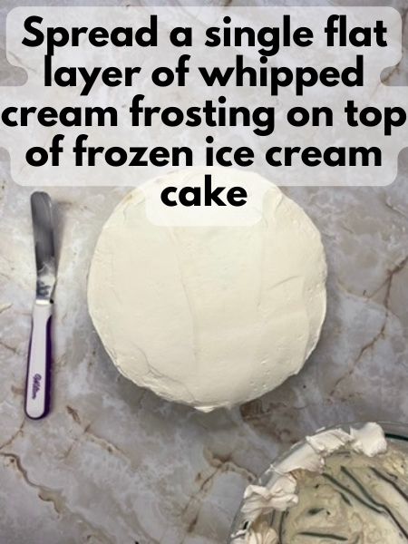 spread whipped cream frosting on top of ice cream cake