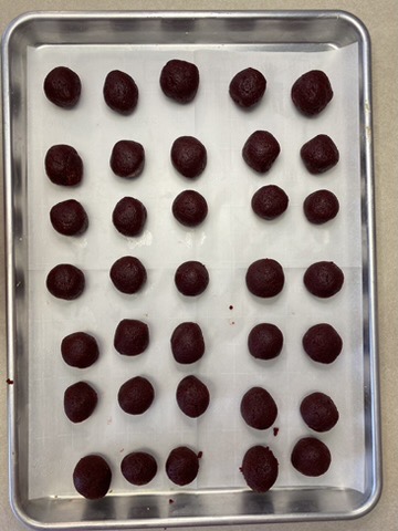 red velvet cake balls sitting on a cookie sheet lined with parchment paper