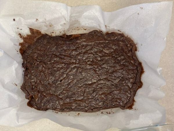 baked brownies in a pan lined with parchment paper