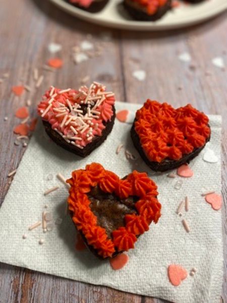 heart brownies decorated with red and pink frosting and Valentine's day sprinkles