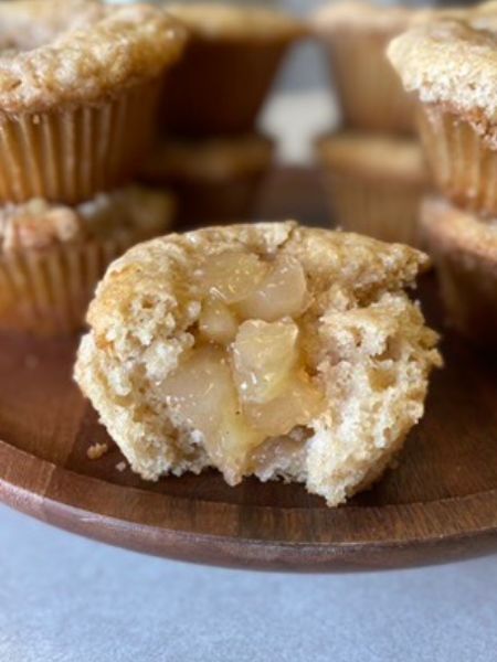 an apple pie muffin with a bite taken out of it, revealing apple pie filling in the middle