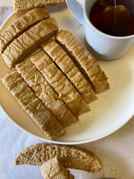 cookie butter biscotti sitting on a plate next to a cupe of tea