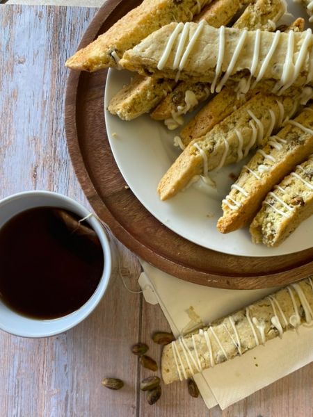 pistachio biscotti on a plate next to a cupe of tea