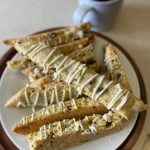 pistachio biscotti on a plate next to a cup of coffee