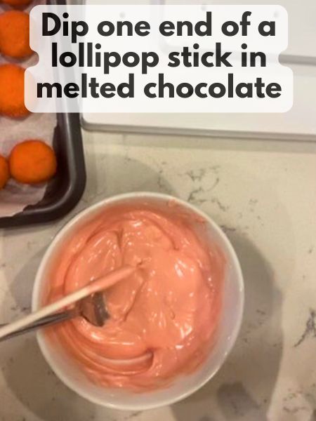 one end of a lollipop stick dipped in melted pink chocolate