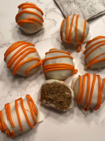 carrot cake balls coated in white chocolate with an orange chocolate drizzle