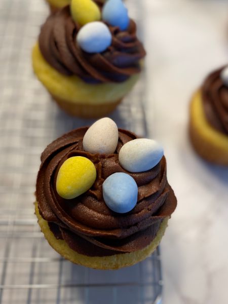 yellow cupcakes with chocolate frosting and decorated with mini chocolate eggs