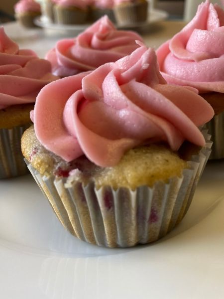 white cupcake base with raspberries baked in and topped with raspberry frosting