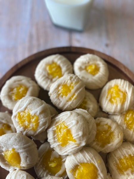 round thumbprint cookies filled with mango filling and topped with a vanilla drizzle