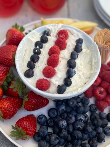 cheesecake fruit dip in a bowl in the center of a larger plate lined with fruits