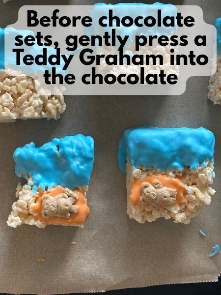 Teddy Graham cracker on top of orange chocolate rectangle on decorated rice krispie treat