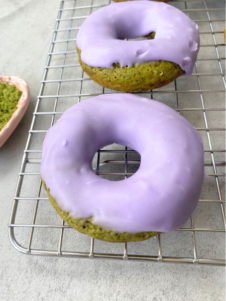 matcha lavender donuts sitting on a cooking rack
