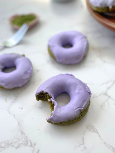 matcha lavender donuts sitting on the counter, a bite is taken out of one