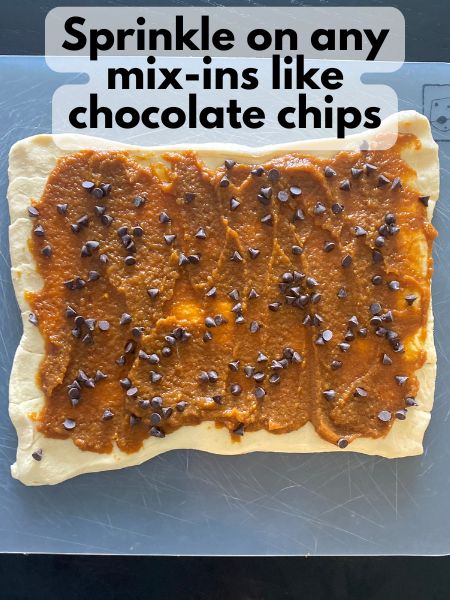 chocolate chips sprinkled over pumpkin filling on crescent dough