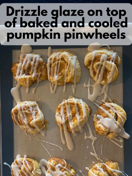 glaze drizzled over baked pumpkin cream cheese pinwheels