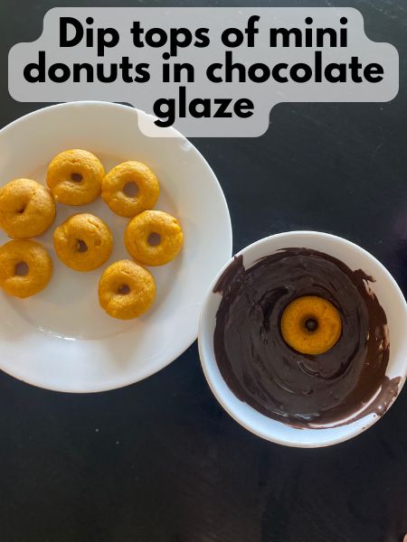 mini pumpkin donut being dipped in melted chocolate