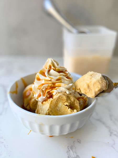 pumpkin ice cream in a bowl with whipped cream and caramel