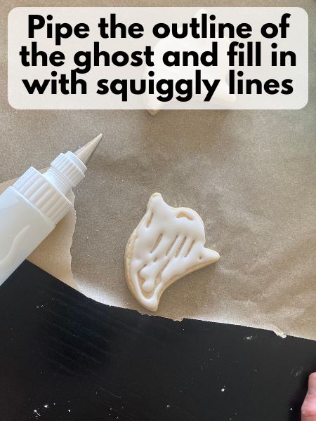 ghost sugar cookie outlined and mostly flooded with royal icing