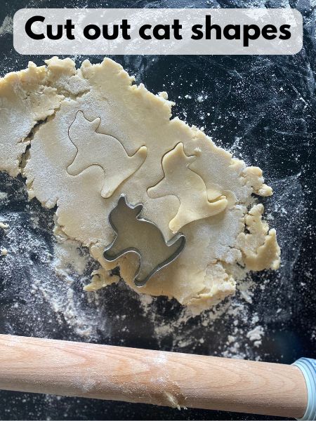 cat cookie cutter cutting shapes out of cookie dough