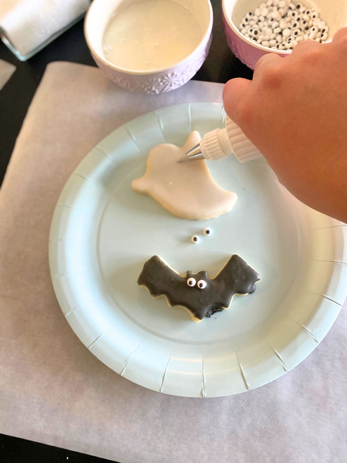 someone decorating a ghost cookie