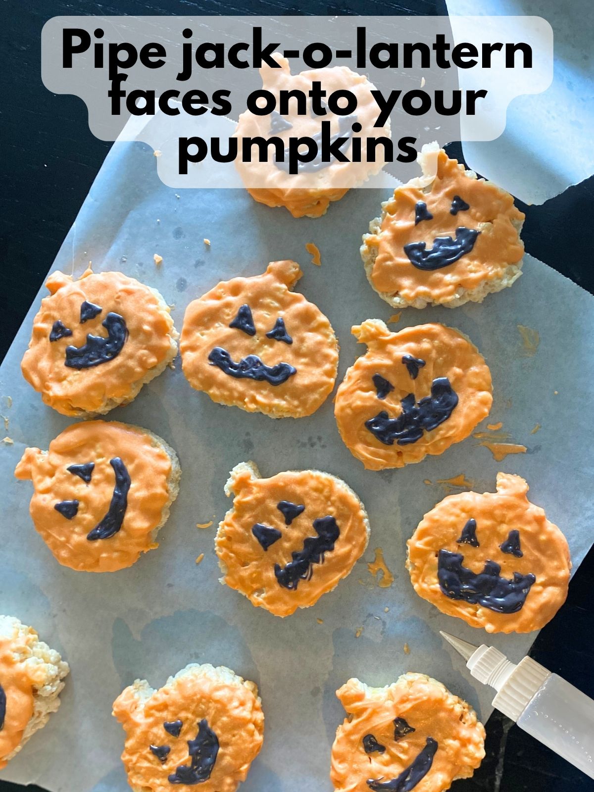 faces drawn onto orange pumpkin rice krispie treats with melted black chocolate