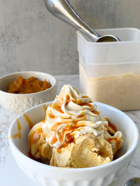 pumpkin ice cream in a bowl with whipped cream and caramel
