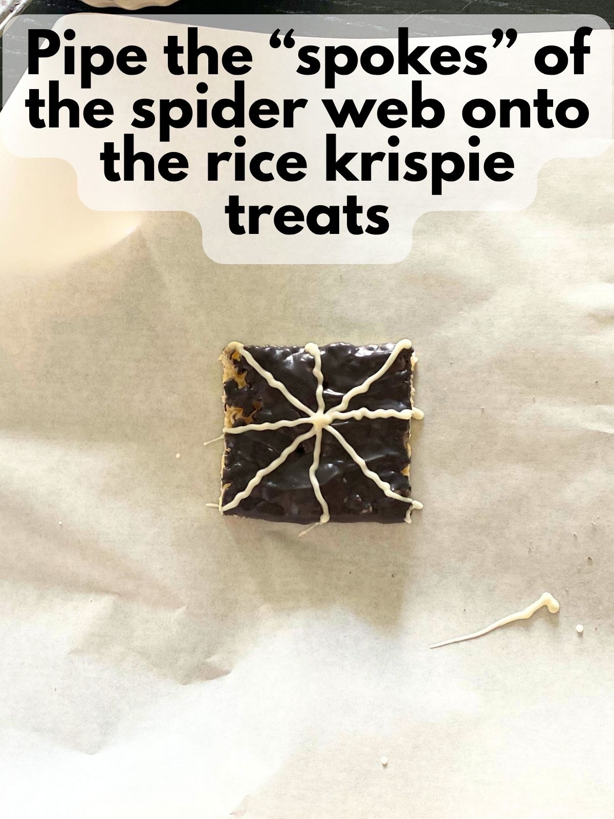 rice krispie treats covered in black chocolate with the spokes of a spider web piped on in white chocolate
