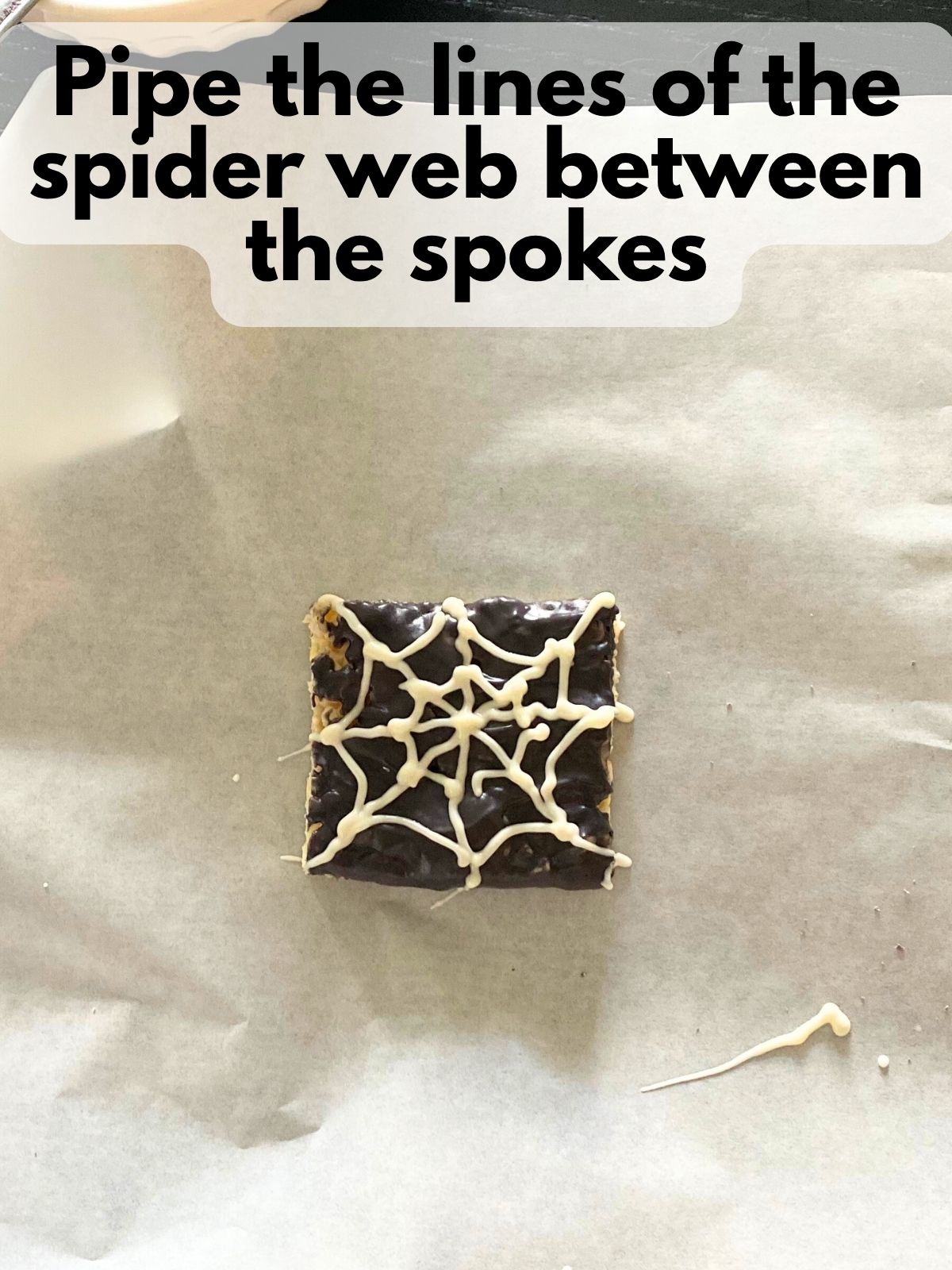 a rice krispie treated dipped in black chocolate with a white spider web piped on top