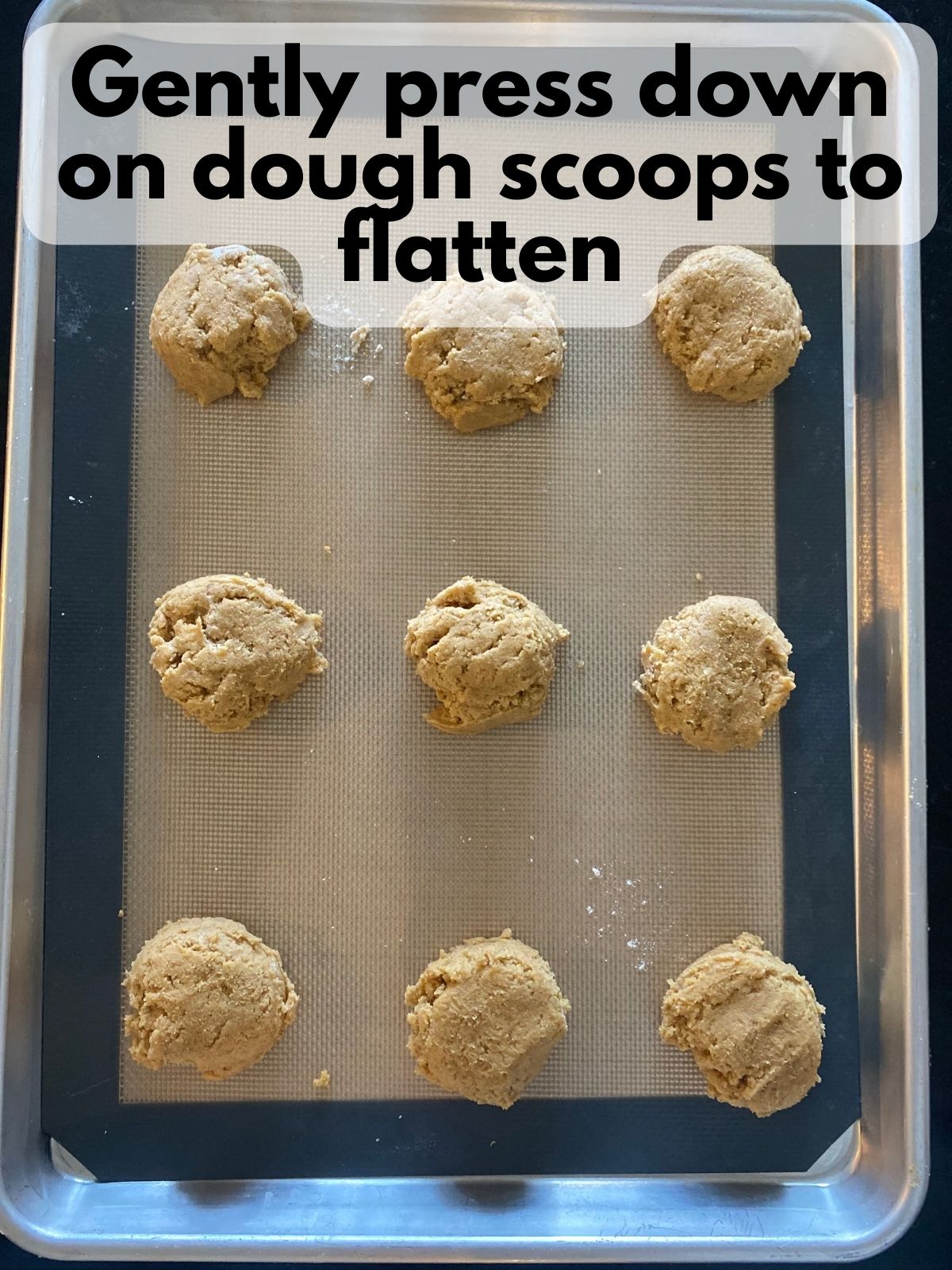 pumpkin sugar cookie dough scooped onto a baking sheet and flattened