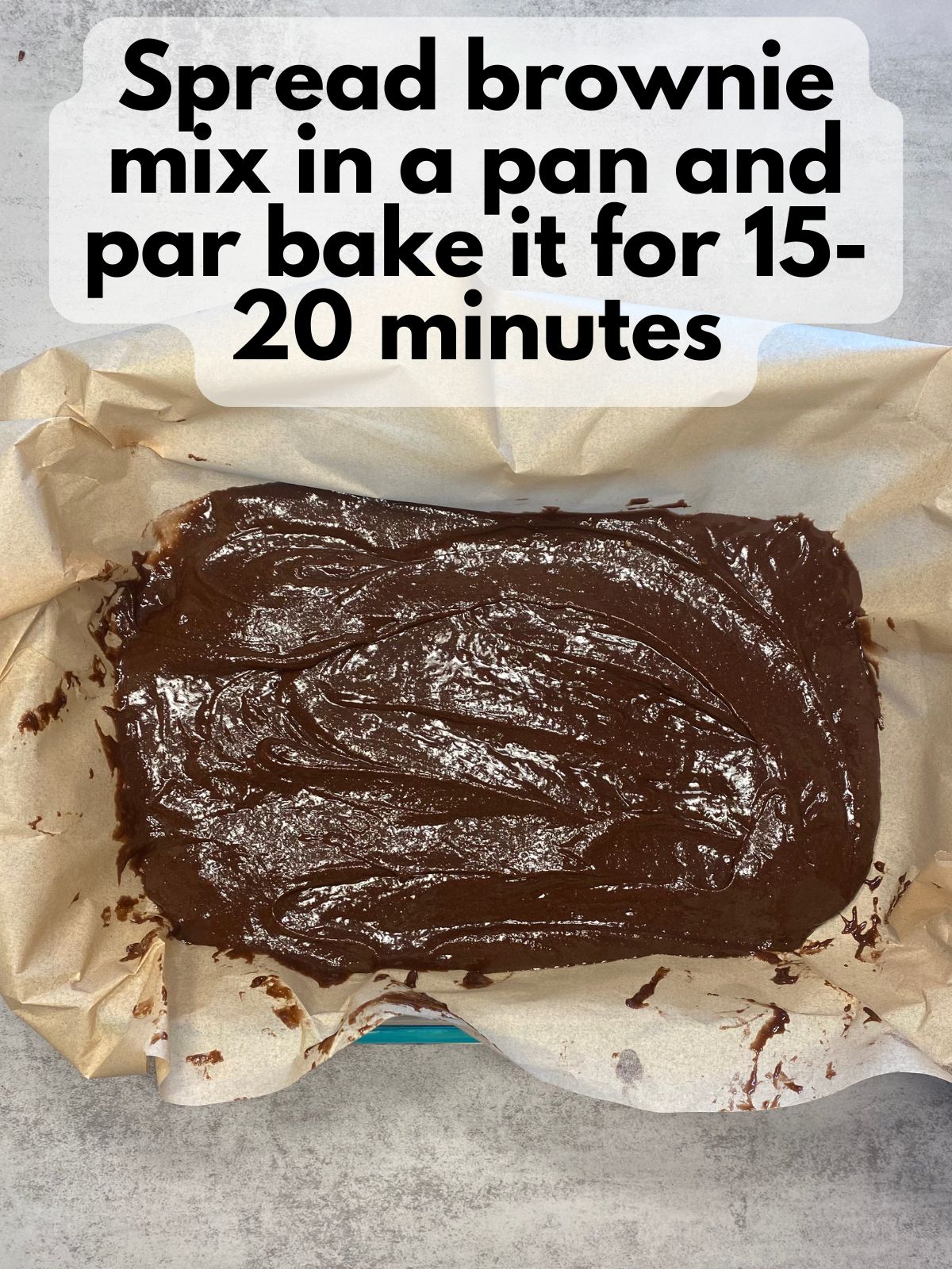 brownie batter in a pan lined with parchment paper