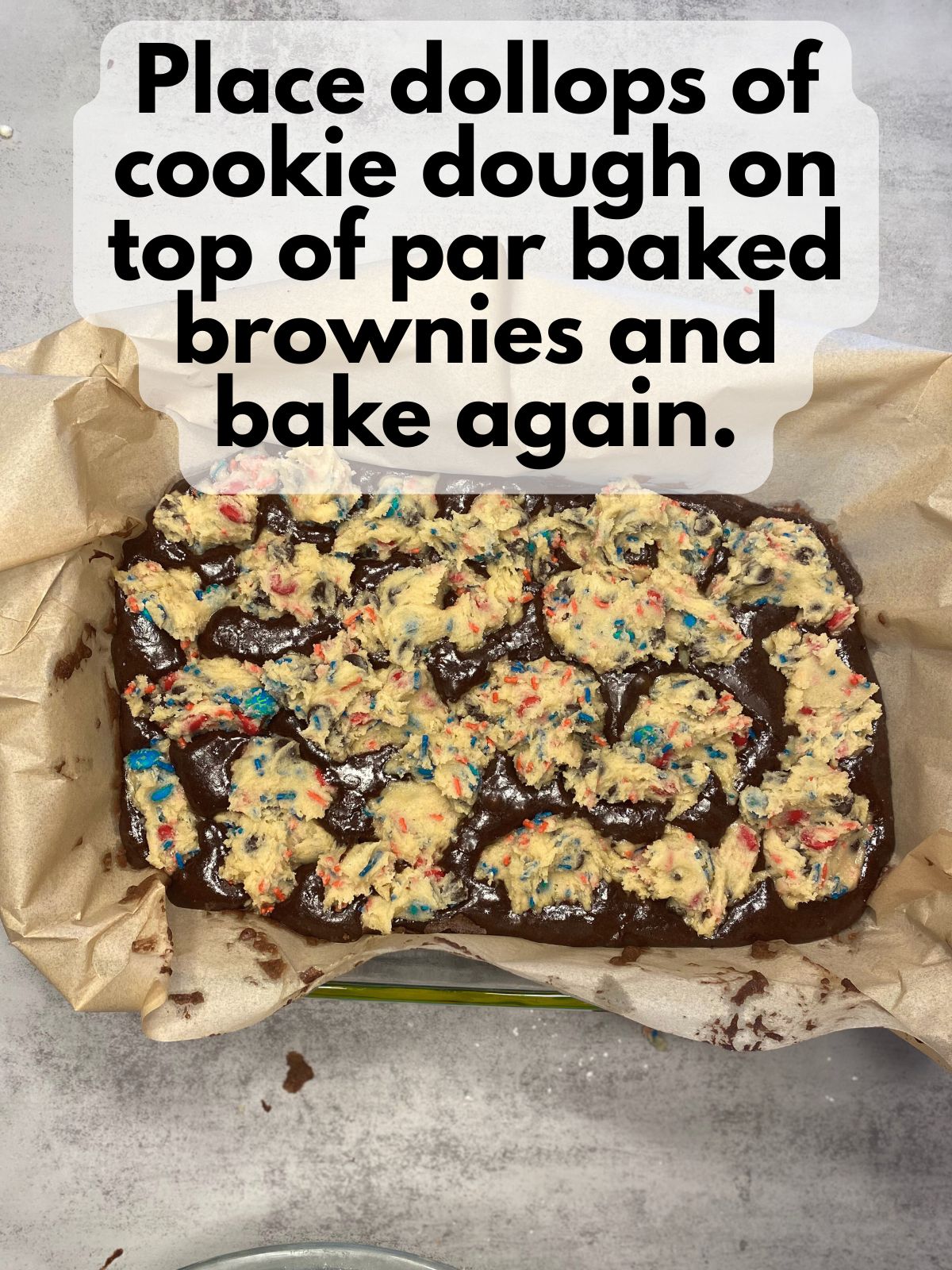 cookie dough dolloped on top of par-baked brownies
