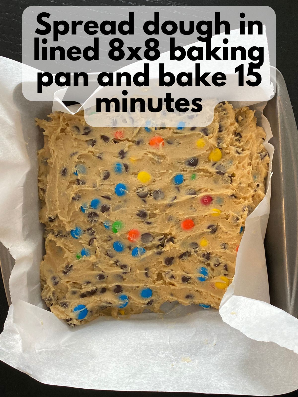chocolate chip M&M cookie dough spread in a pan