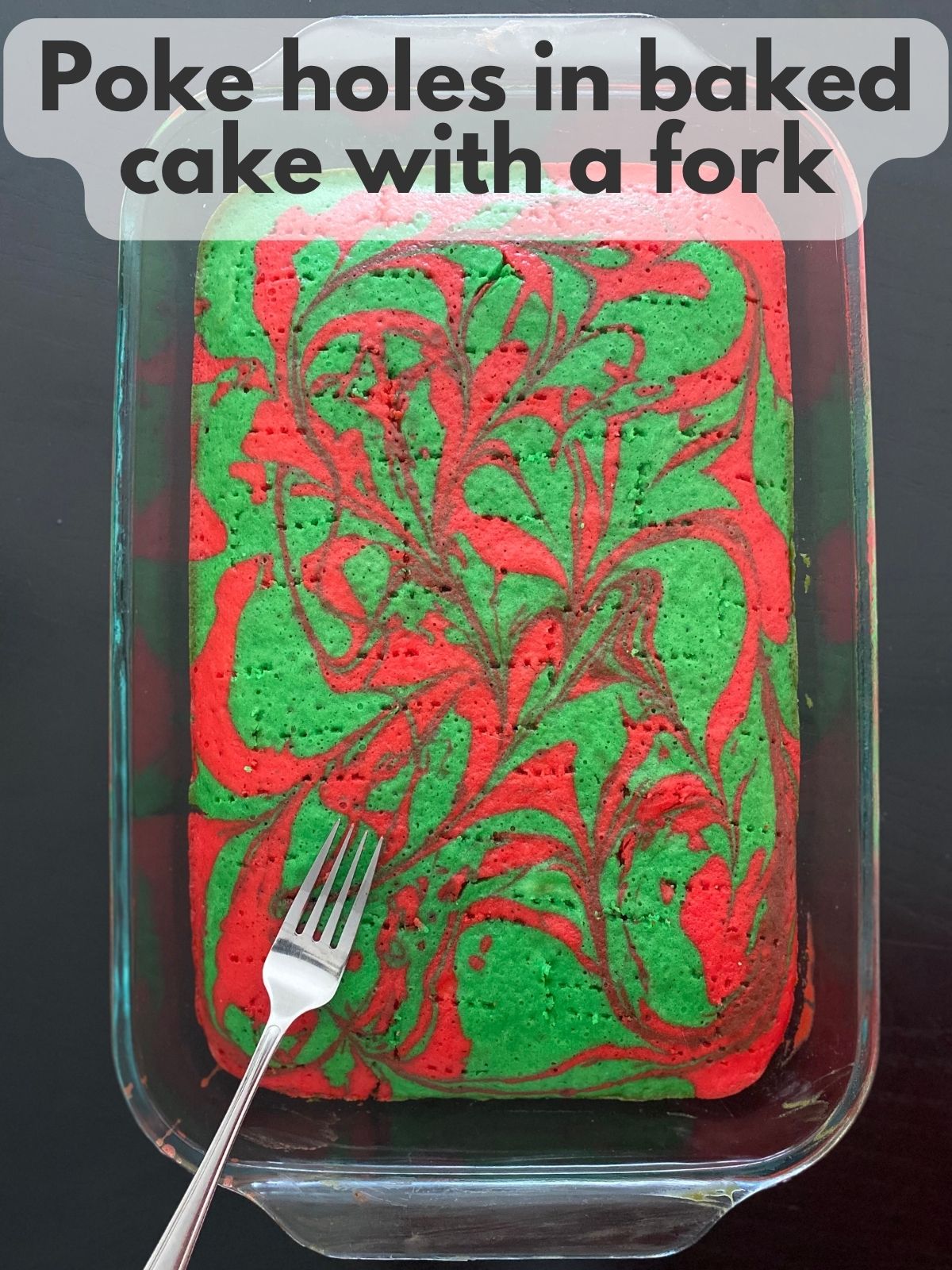 baked red and green marbled cake with holes poked in it