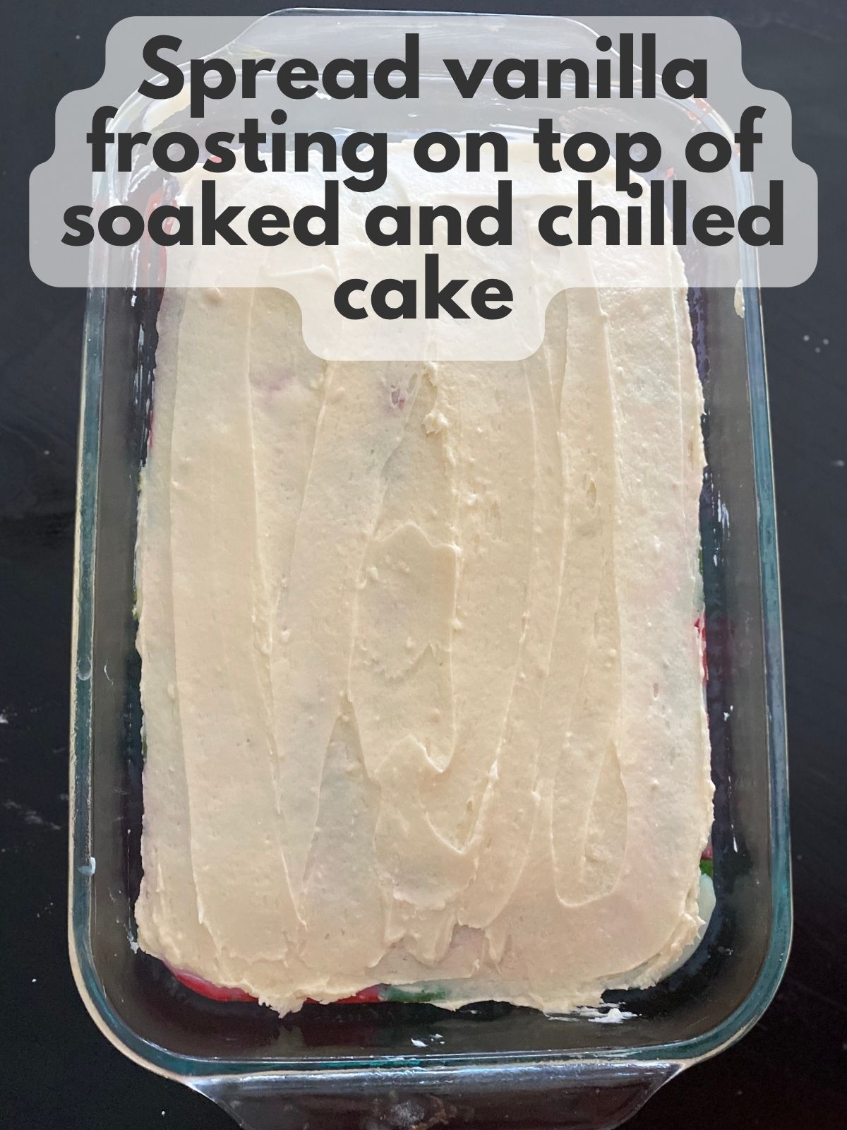 vanilla buttercream spread on top of soaked Christmas poke cake
