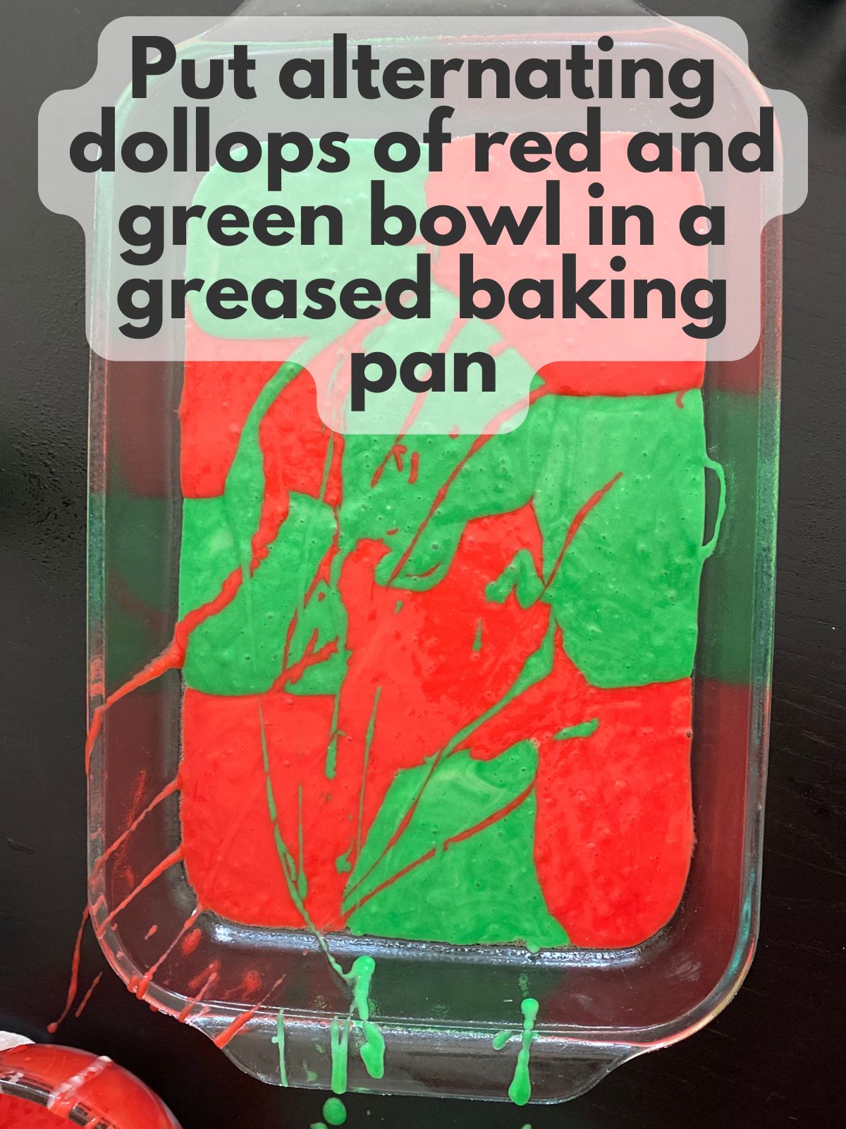 red and green batter dolloped in a greased 9x13 baking pan