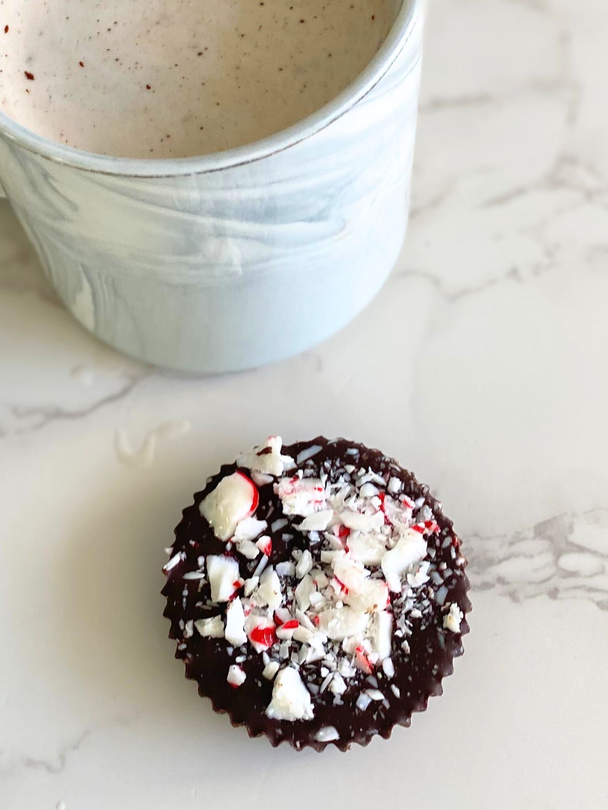 Christmas hot chocolate puck sitting next to a mug of hot chocolate