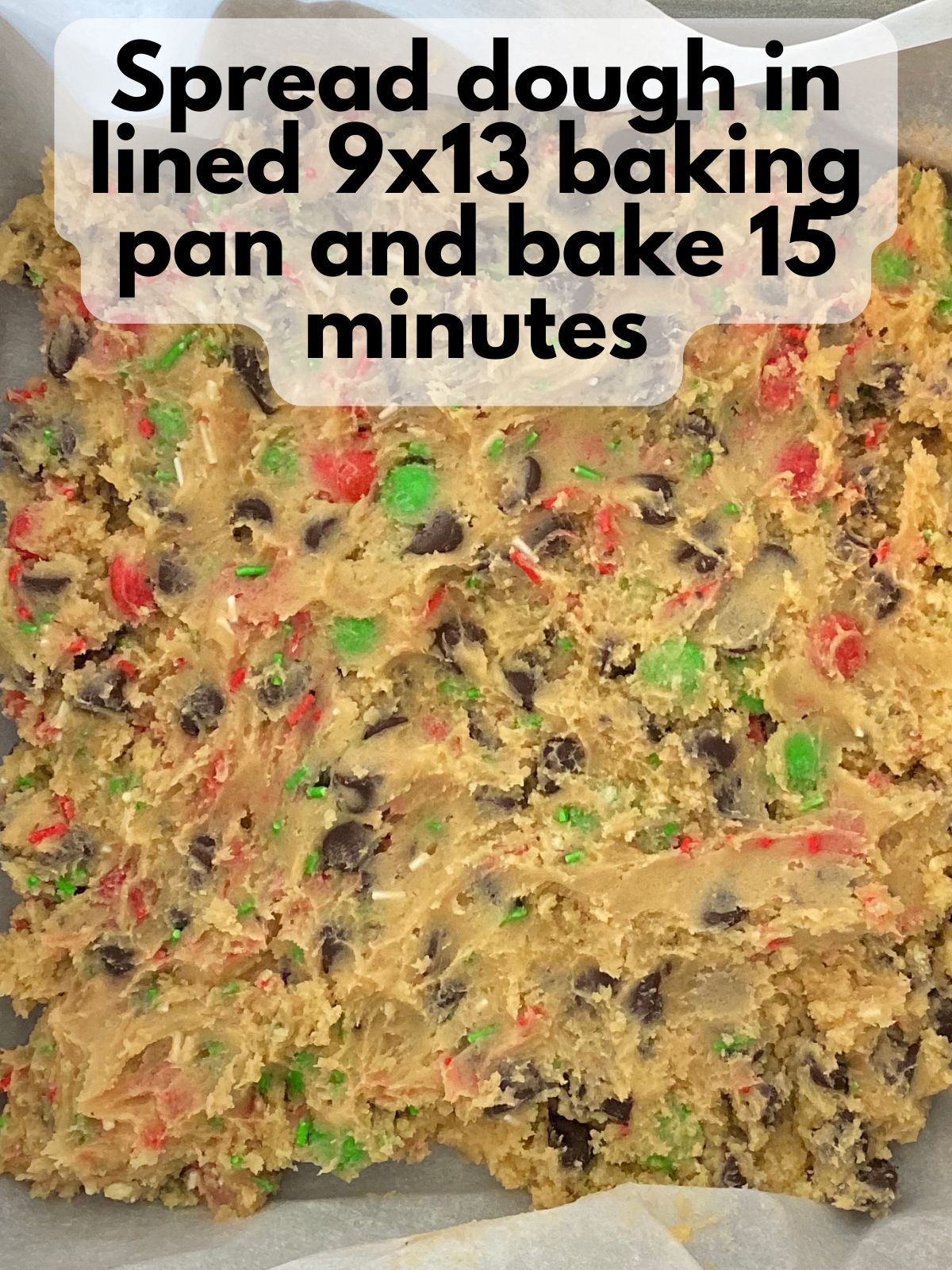 Christmas M&M cookie bar dough spread in a 9x13 pan
