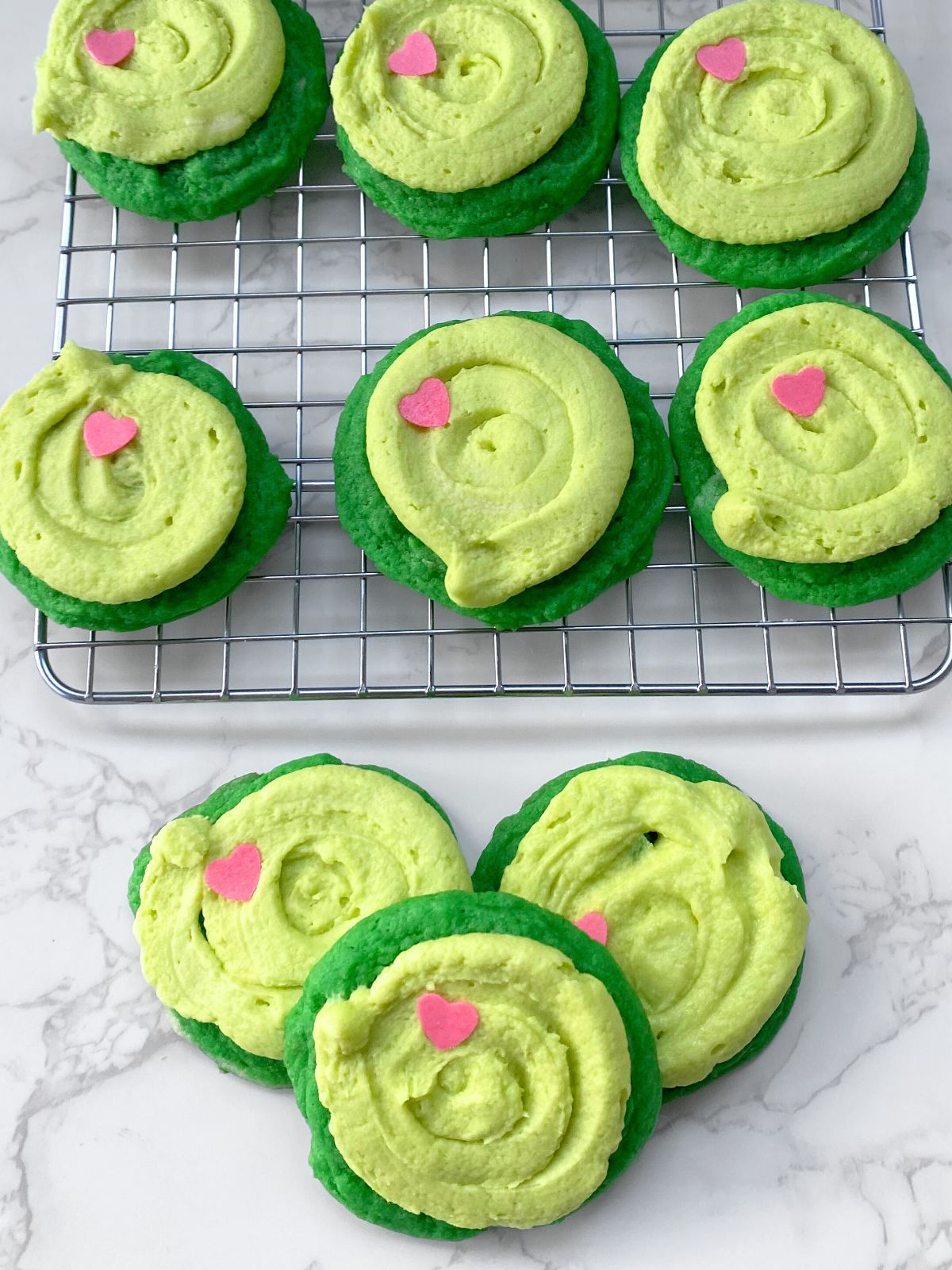 green sugar cookies with light green frosting and a heart candy on top