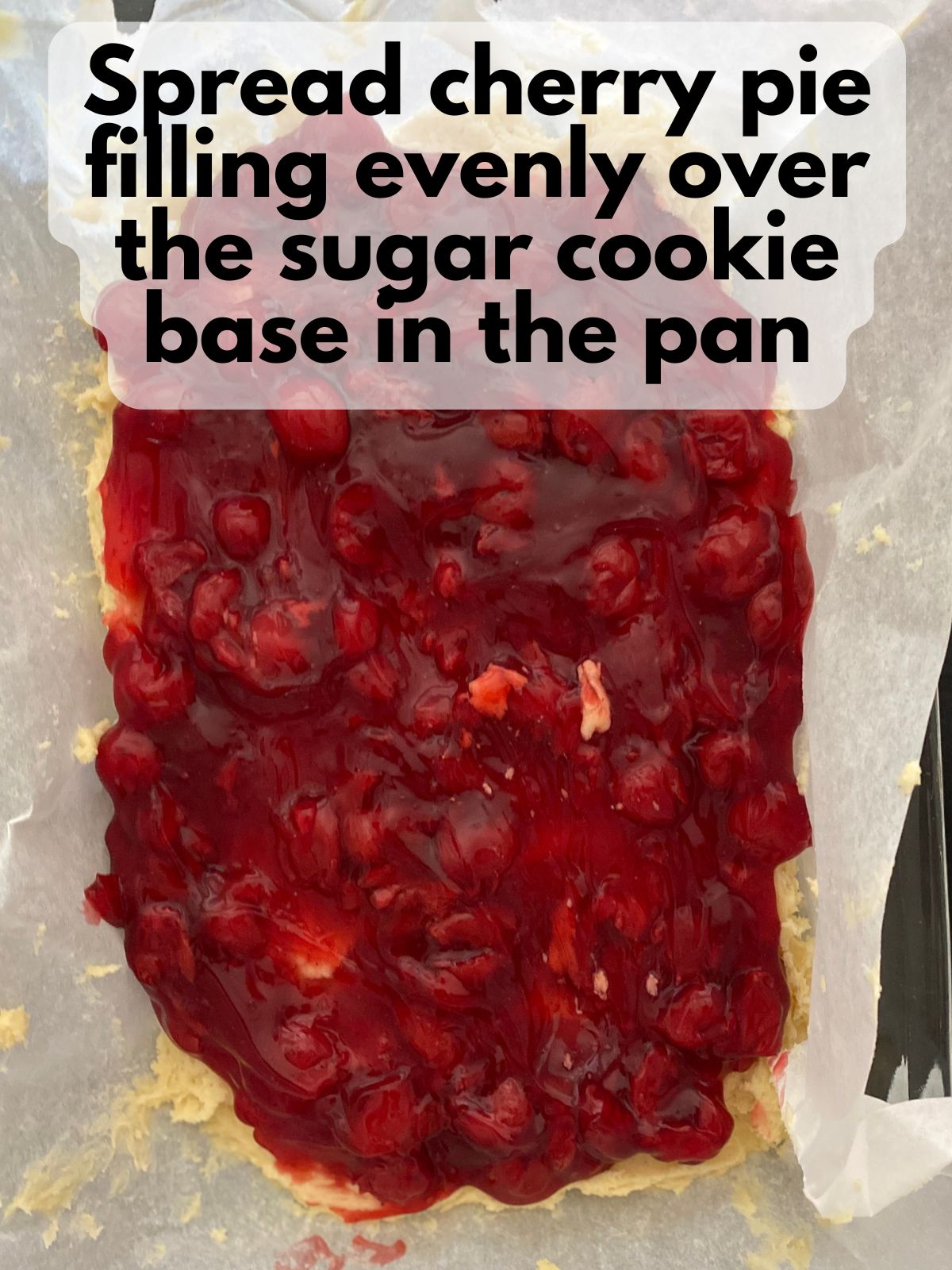 cherry pie filling spread on top of sugar cookie dough in 9x13 pan