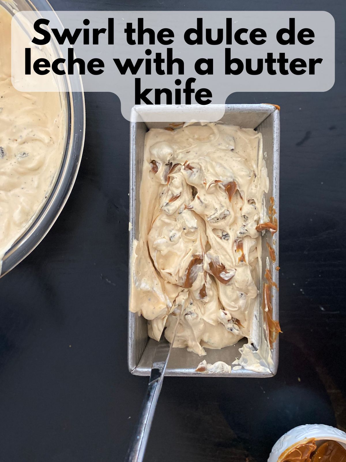 a butter knife swirling dulce de leche through ice cream in a loaf pan