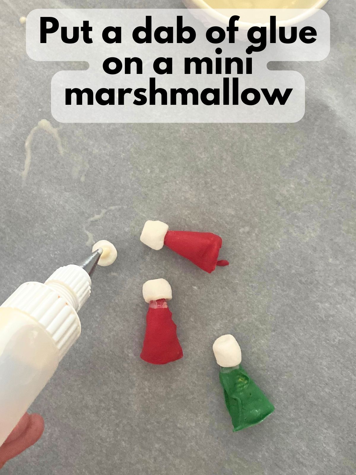 white chocolate being dabbed onto mini marshmallows like glue