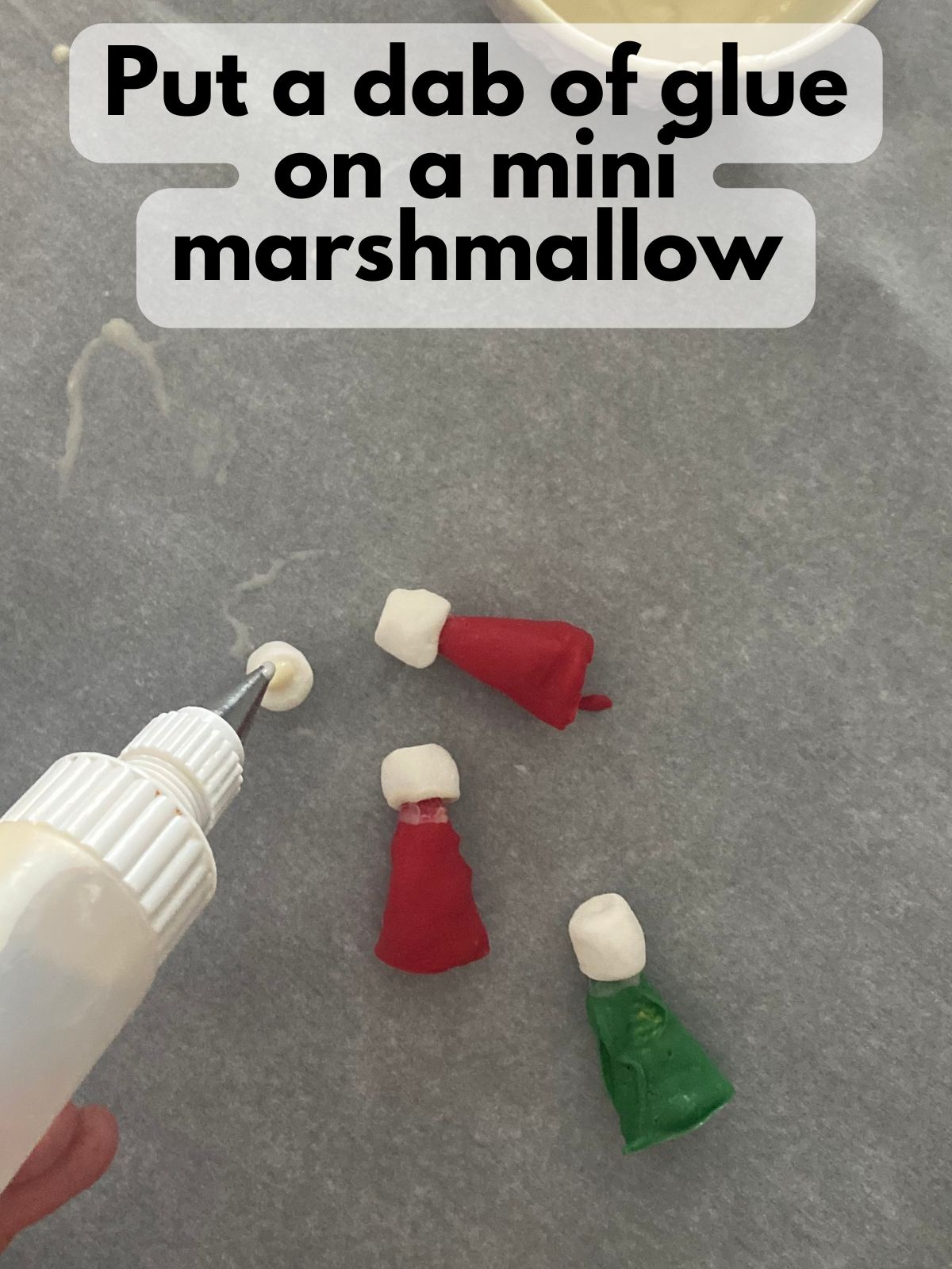 small squeeze top bottle placing a dab of glue on a mini marshmallow