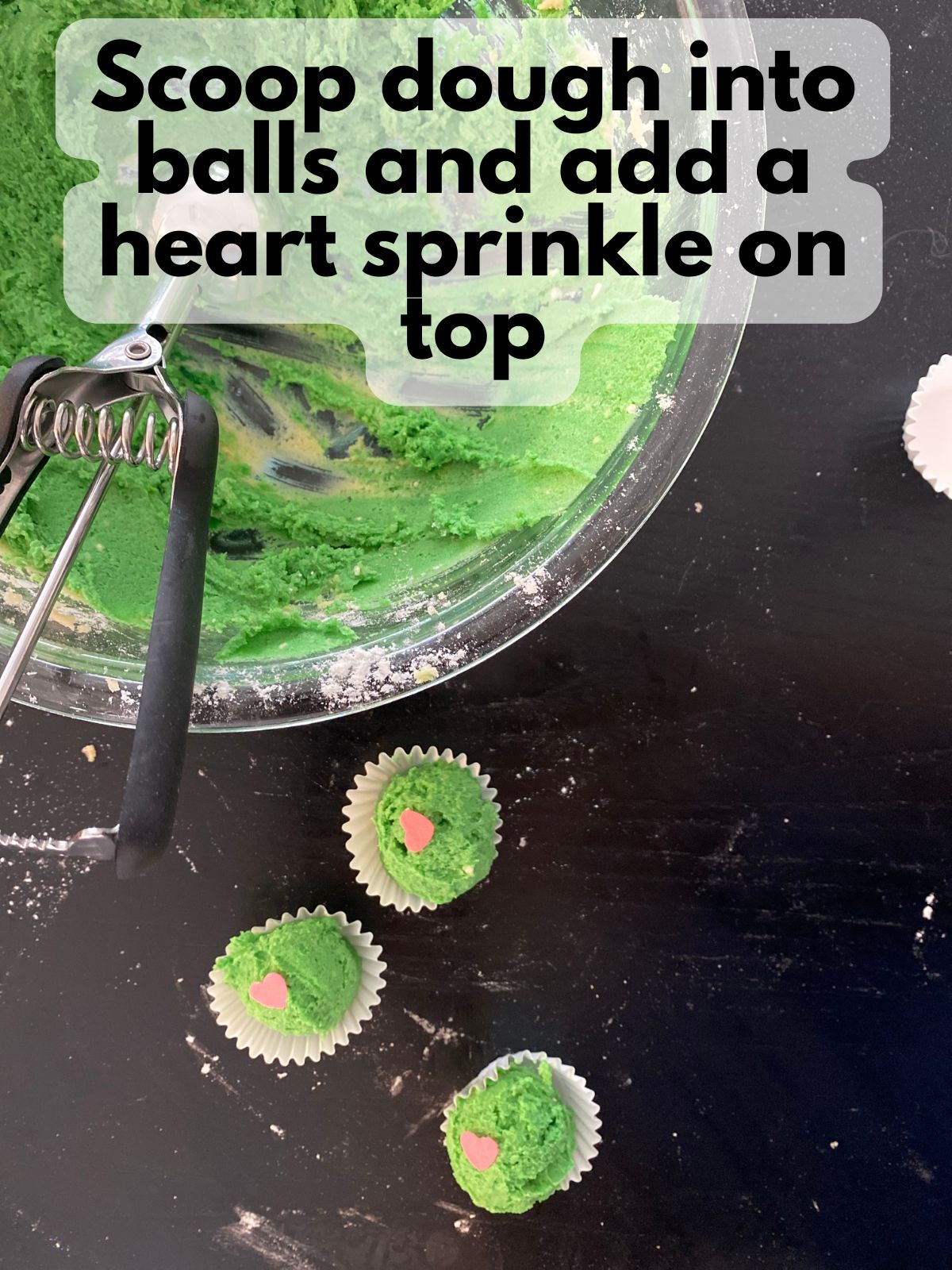 cookie dough balls scooped into mini cupcake liners with a heart sprinkle on top
