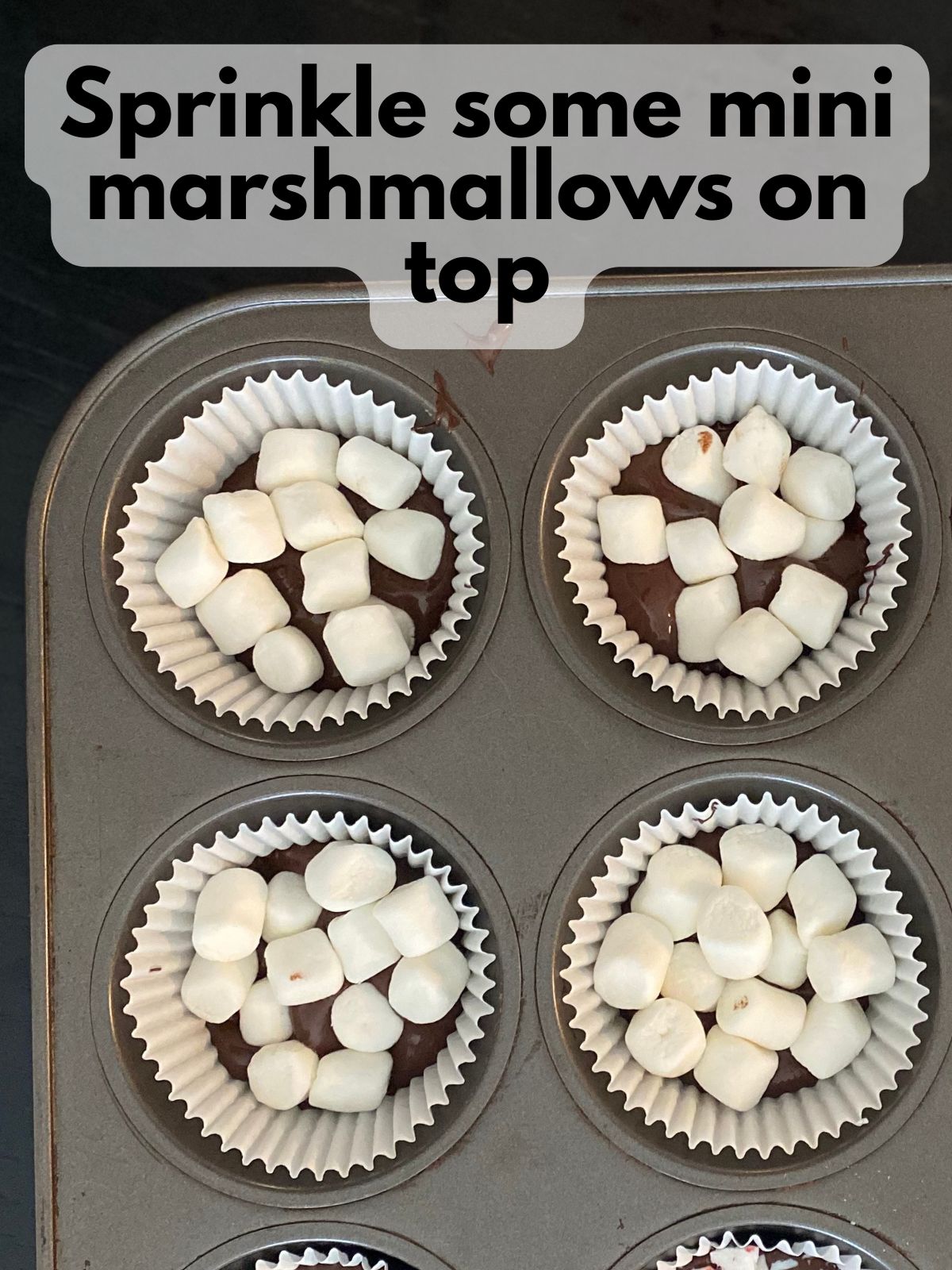 mini marshmallows on top of melted chocolate in a cupcake tin
