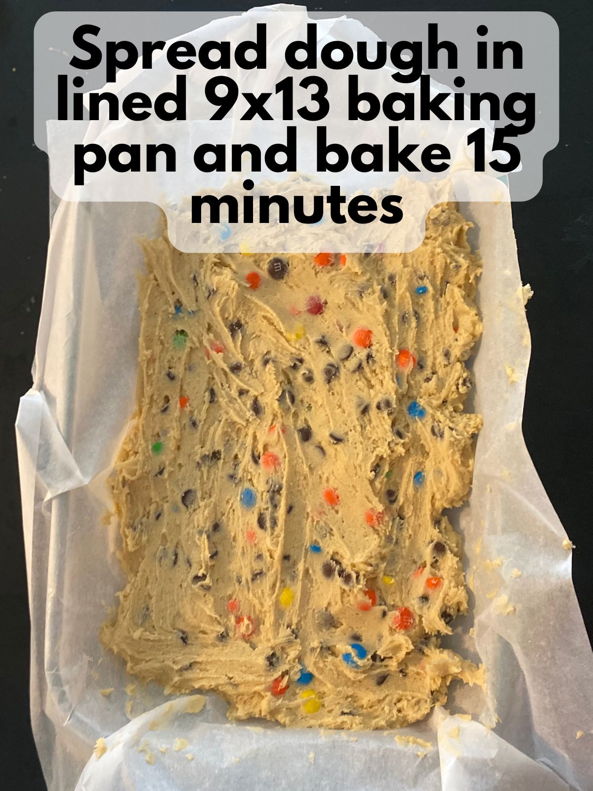 M&M cookie bar batter spread in a 9x13 pan
