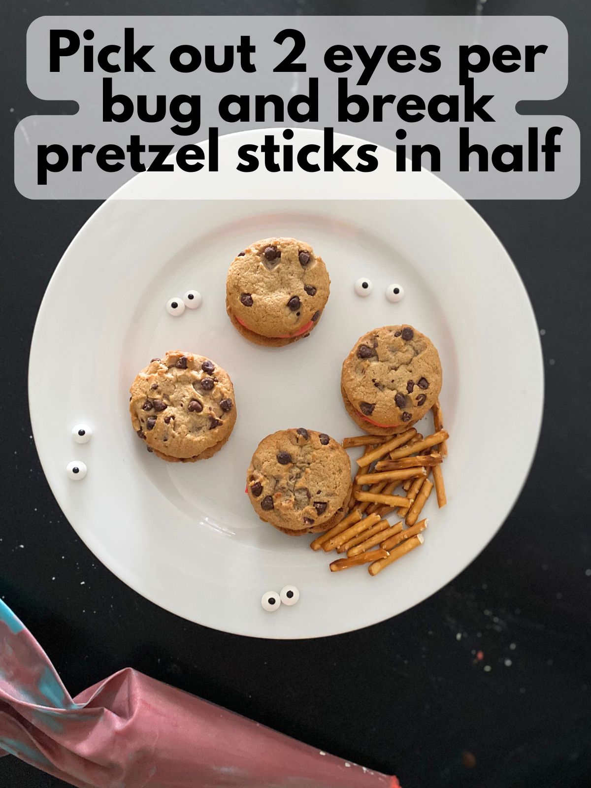 pairs of candy eyes and pretzel sticks next to cookie sandwiches