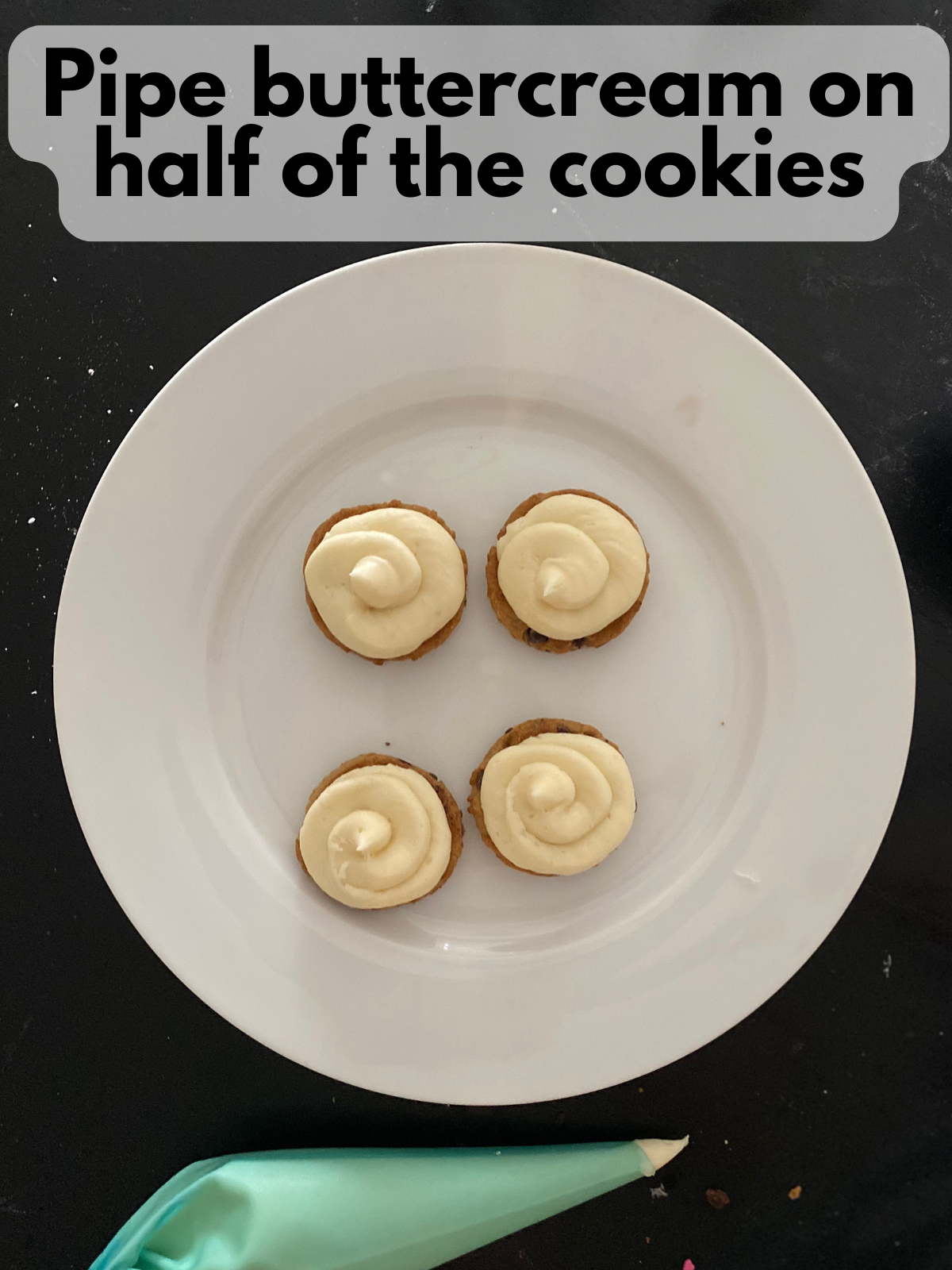 vanilla buttercream piped on top of chocolate chip cookies